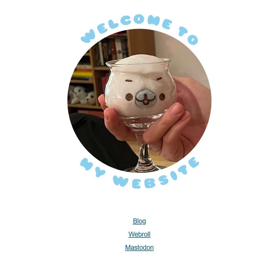 My new front page, with links to my blog, webroll, Mastodon, and most prominently: a circular photo of a seal plush stuffed into a wine glass, with "Welcome to my website" written in balloon letters around the photo.